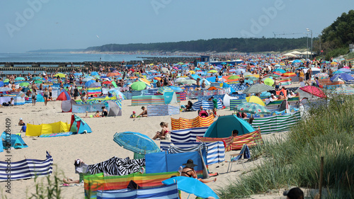 Parasol słoneczny na plaży nadmorskiej w wakacje razem z parawanem na wiatr. 