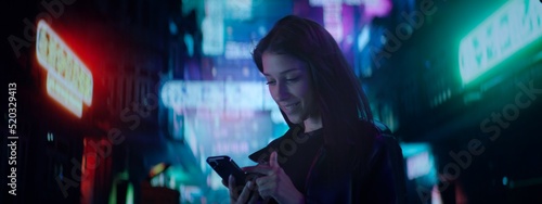 Photography CU Night portrait of Hispanic female using her mobile phone in the street filled with neon signs