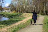 Kobieta z psem na spacerze drogą wzdłuż rzeki.