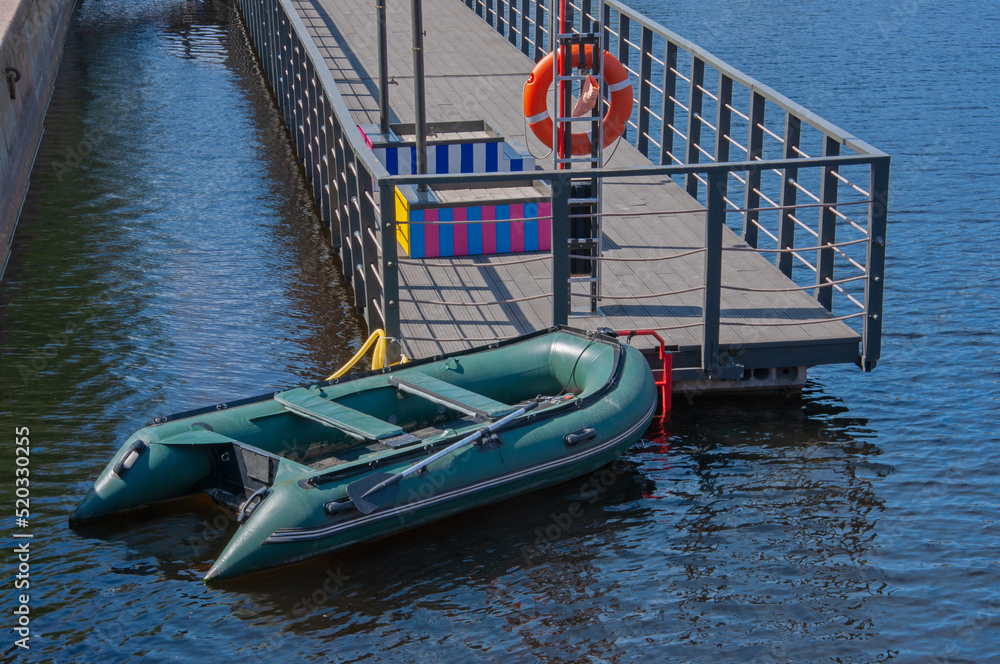 Inflatable boat and red life buoy on a wooden boat pier by the sea