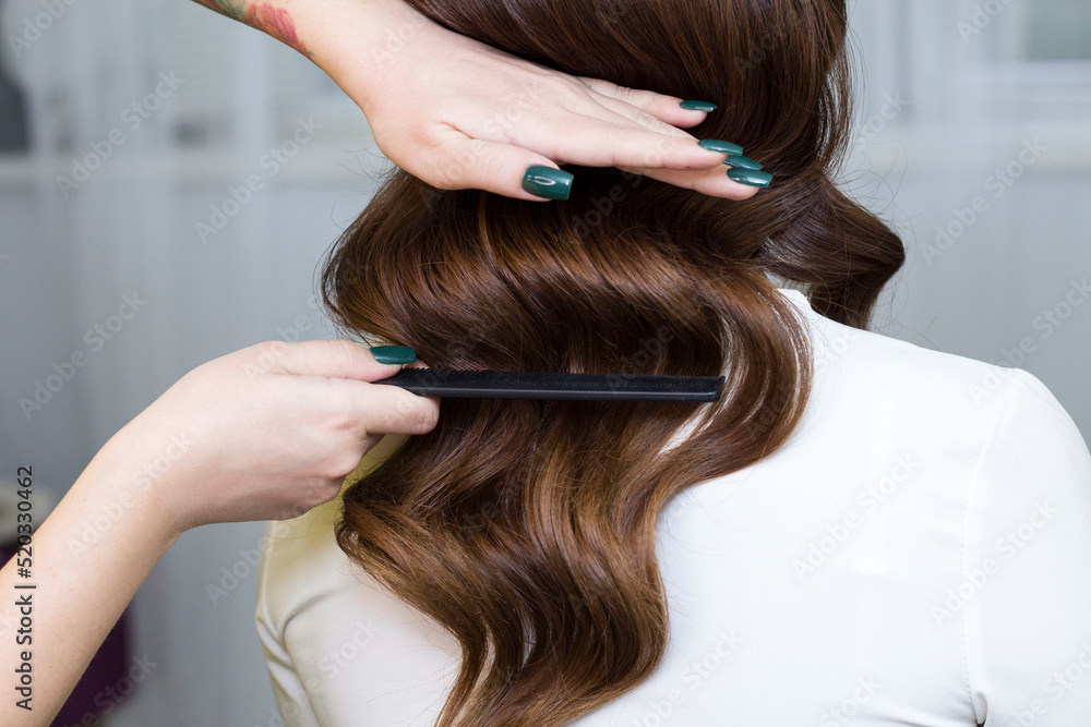 Fototapeta premium A beautiful girl does styling in a beauty salon. Hollywood curls. Hairstyle
