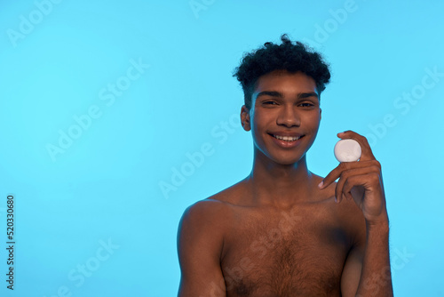 Smiling black guy holding and showing dental floss