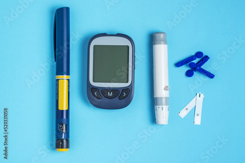 Measuring blood sugar. Glucometer, insulin pen, lancet and test strip on a blue background.
