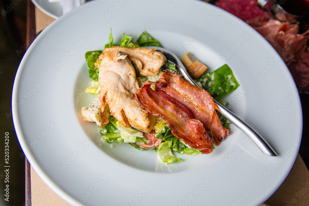 Salad with meat in a bowl. The waiter is holding a plate of salad close-up. Salad with meat in a bowl. The waiter is holding a plate of salad close-up.