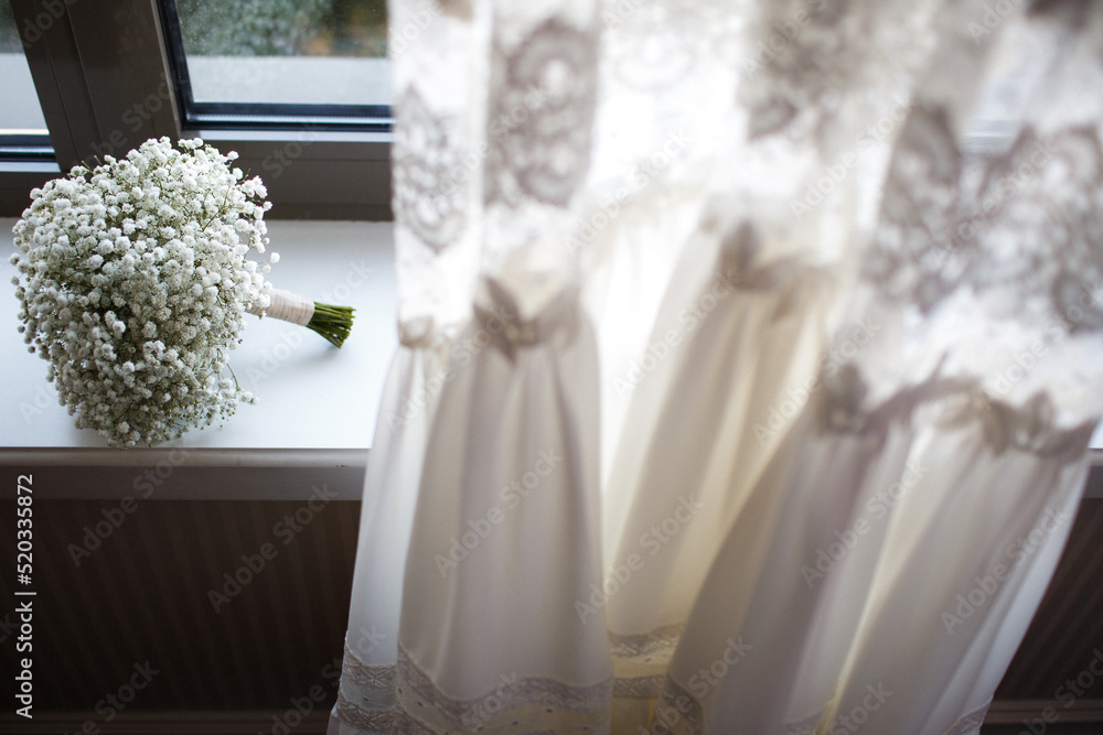 Delicate bouquet on the windowsill near the wedding dress Delicate bouquet on the windowsill near the wedding dress