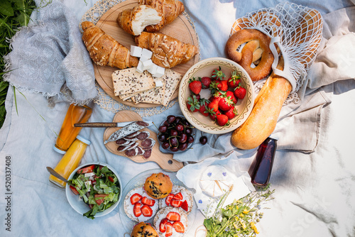 Picnic in the field with berries, juice, cheese, sausage and sweet croissants
