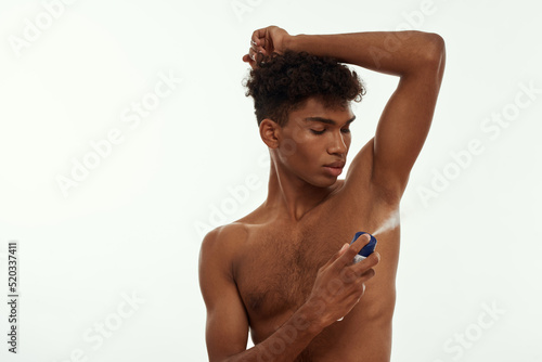 Black guy applying spray deodorant on his armpit