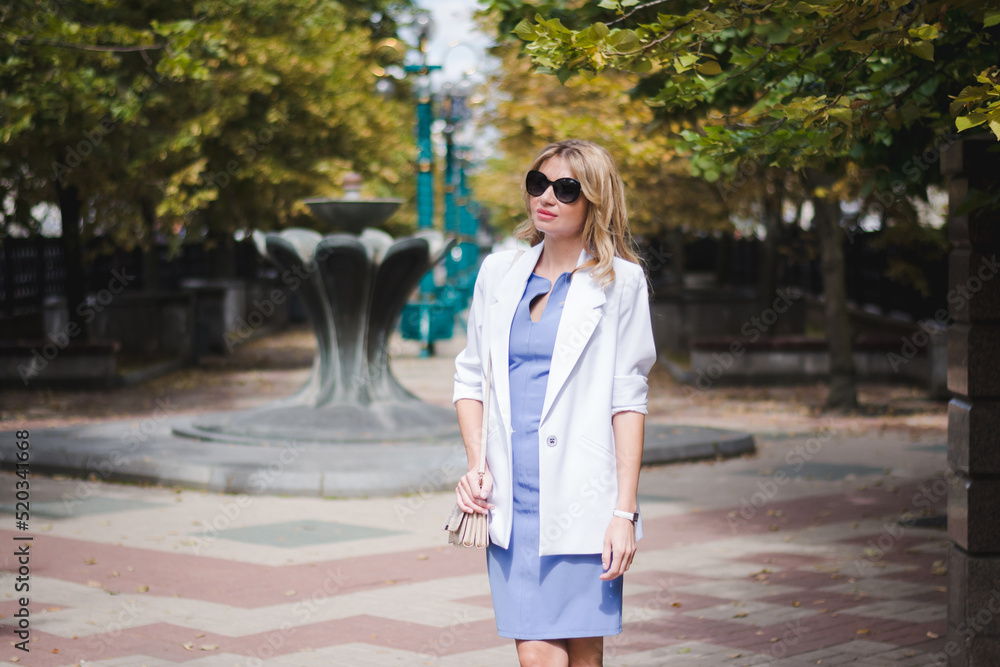 Stylish beautiful business woman in a white jacket on the street