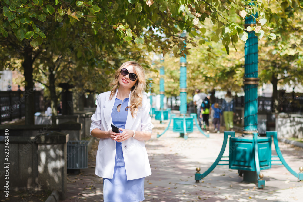 Stylish beautiful business woman in a white jacket on the street