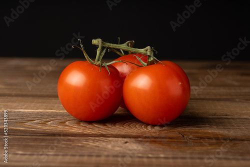 Red ripe tomatoes lie on an oak table.