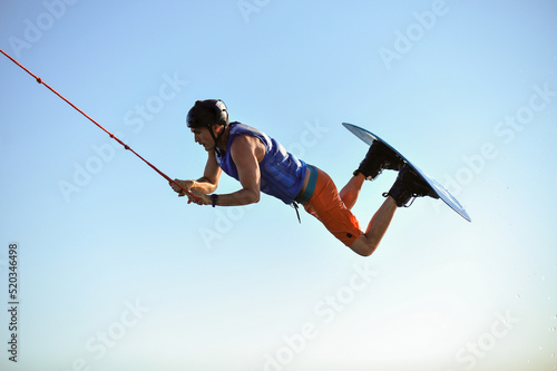 Photography Professional wakeboarder jumping over the water against the sky and trees