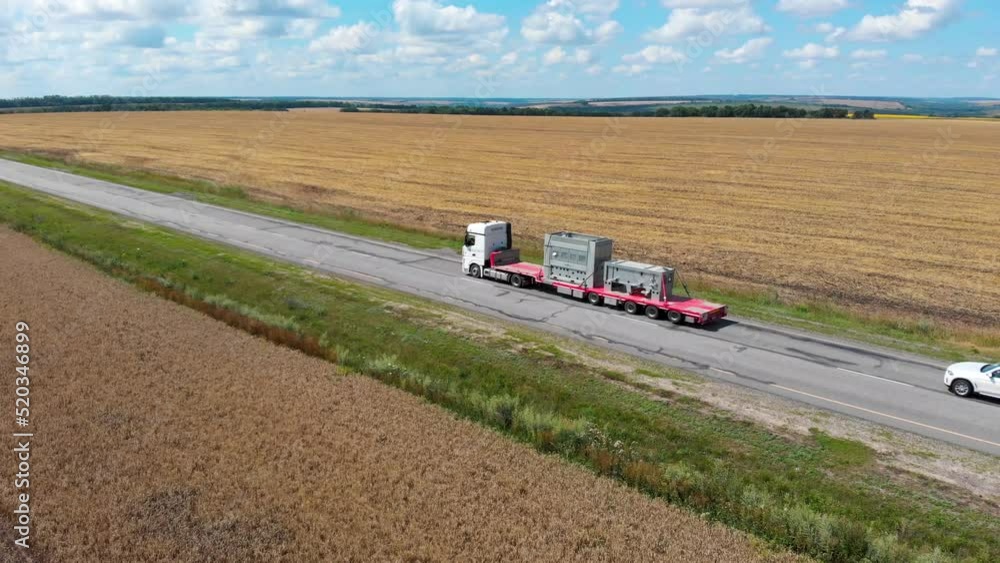Field of grain crops. Highway. The movement of trucks. In the country. Shooting from a drone. Sunny day. Green grass. Europe. Summer. Agriculture. Farm plantations. Agro. Background. Field of grain crops. Highway. The movement of trucks. In the country. Shooting from a drone. Sunny day. Green grass. Europe. Summer. Agriculture. Farm plantations. Agro. Background.