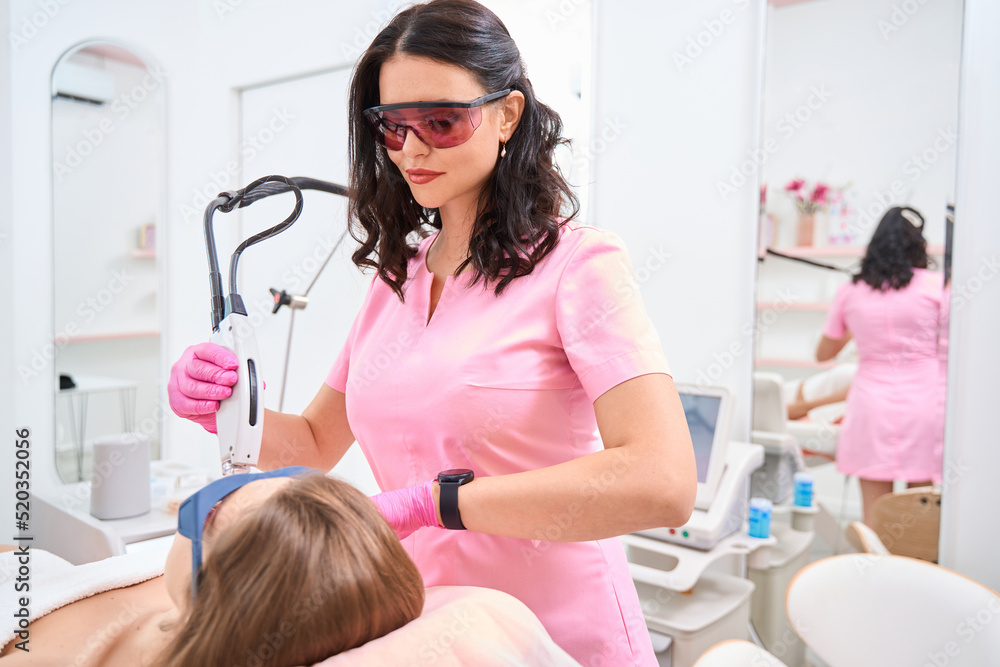Doctor works with laser to remove hair on female face Doctor works with laser to remove hair on female face
