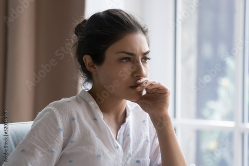 Canvas Print Serious thoughtful beautiful Indian woman sitting on couch indoors, touching chi