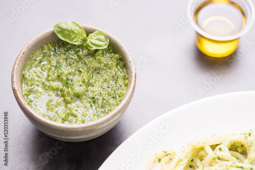 Fresh Italian basil pesto sauce and mini basil in green sauce cup with basil pesto pasta, olive oil on the gray background.