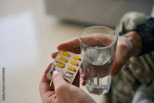 Tableau sur toile Glass of water and antidepressant medication in hands of soldier