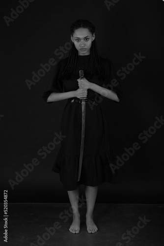 Beautiful curly woman with a katana sword in darkness in black and white