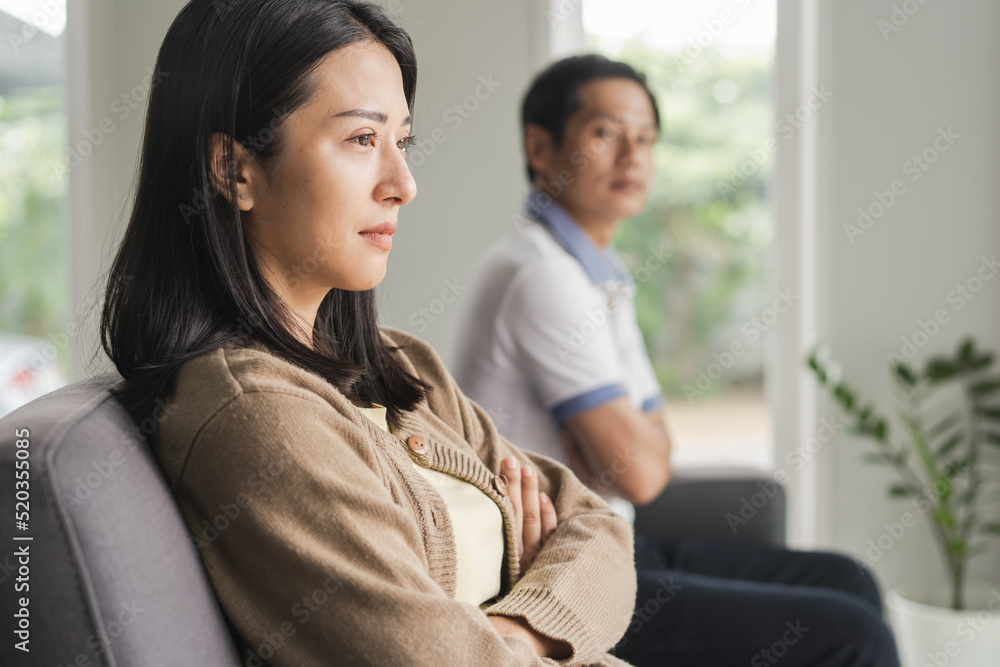 Asian couple having relation problem. Wife crying and sitting separate with her husband at home after quarrel. Asian couple having relation problem. Wife crying and sitting separate with her husband at home after quarrel.
