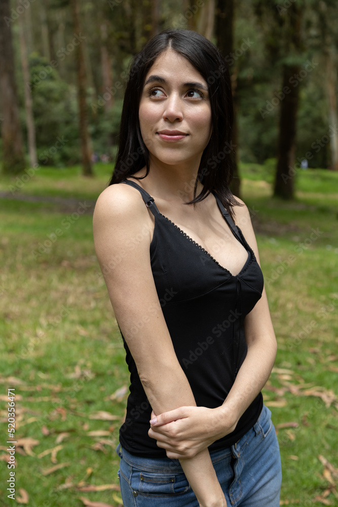 portrait of young woman with straight black hair wears a black top with cleavage, nature and beauty of latin model in a park portrait of young woman with straight black hair wears a black top with cleavage, nature and beauty of latin model in a park
