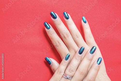Closeup of beautiful groomed woman's hands with green spring summer nail design on red background. Manicure, pedicure beauty salon concept. copy space for text. Long nails with swamp - gel polish.