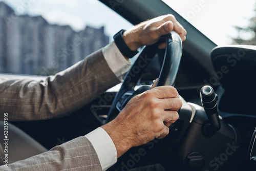 Close-up of man holding hands on steering wheel while driving a car