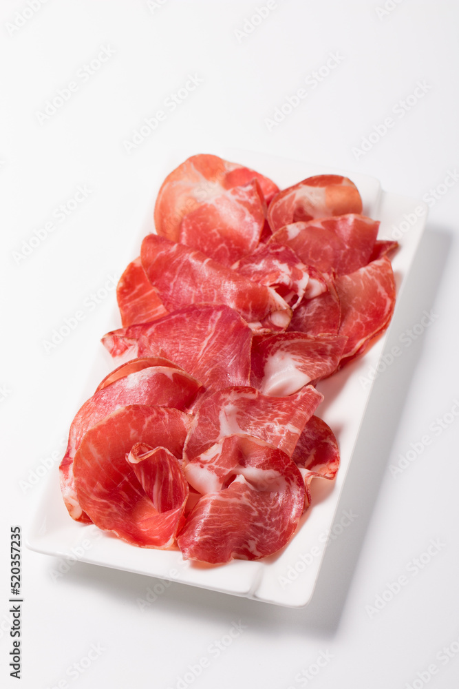 Italian slices of coppa, capocollo, capicollo or cured ham with rosemary. Raw food. Italian slices of coppa, capocollo, capicollo or cured ham with rosemary. Raw food.