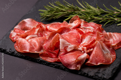 Italian slices of coppa, capocollo, capicollo or cured ham with rosemary. Raw food.   photo