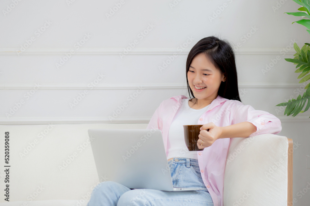 Young asian business woman work from home with laptop computer and drinking coffee on sofa in living room, freelance girl using notebook sitting on couch with comfort and relax, lifestyles concept. Young asian business woman work from home with laptop computer and drinking coffee on sofa in living room, freelance girl using notebook sitting on couch with comfort and relax, lifestyles concept.