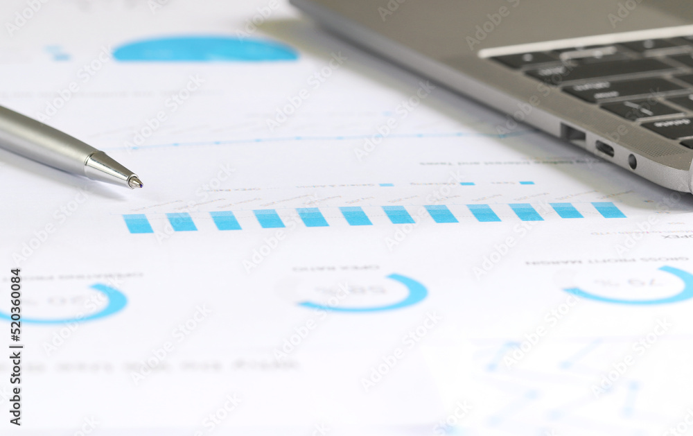Financial charts on office desk with laptop, home office work space. financial accounting strategy analysis concept Financial charts on office desk with laptop, home office work space. financial accounting strategy analysis concept