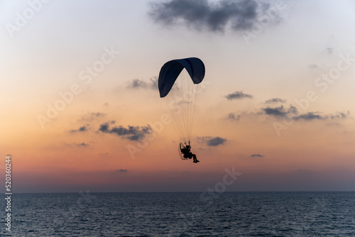 Men fly on parachute at sunshine