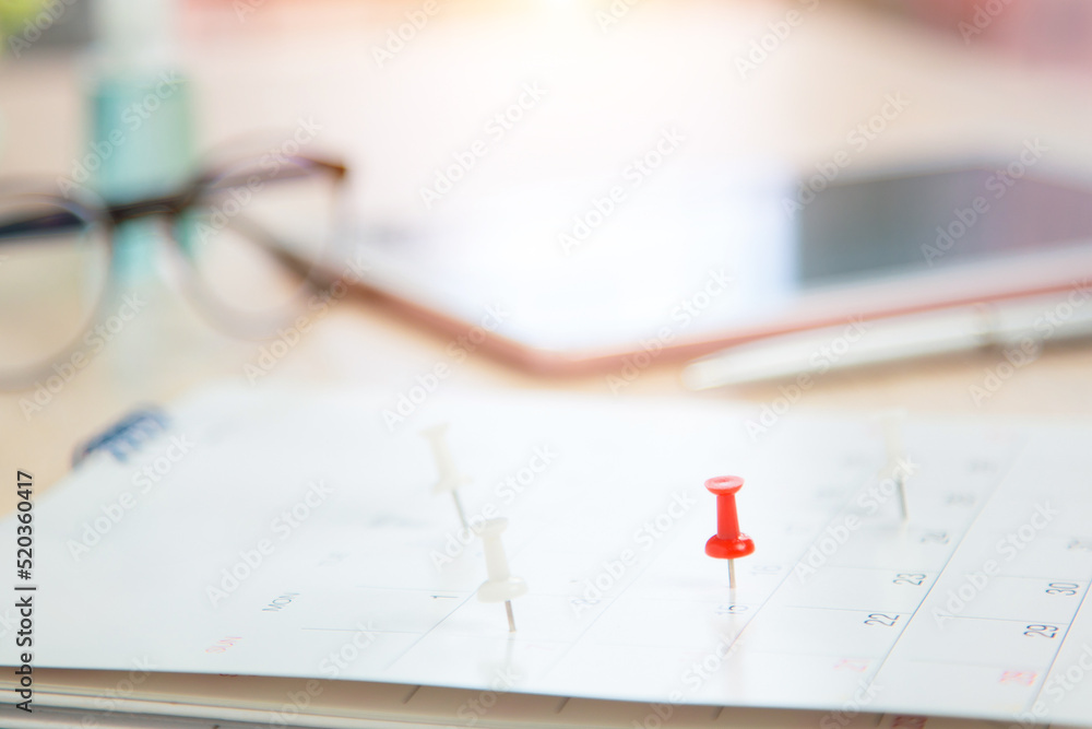 Close up pin on business desk calendar with office equipment concept of event planner or personal organization reminder and schedule or planning. Close up pin on business desk calendar with office equipment concept of event planner or personal organization reminder and schedule or planning.
