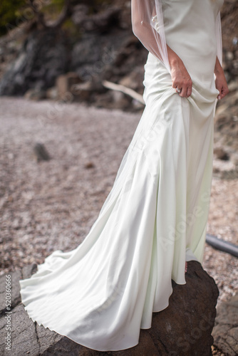 The bride in a wedding dress stands on a stone