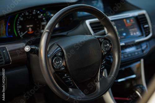 Black luxury modern car interior. Steering wheel, speedometer, display, and multimedia dashboard. Detail of car interior inside.