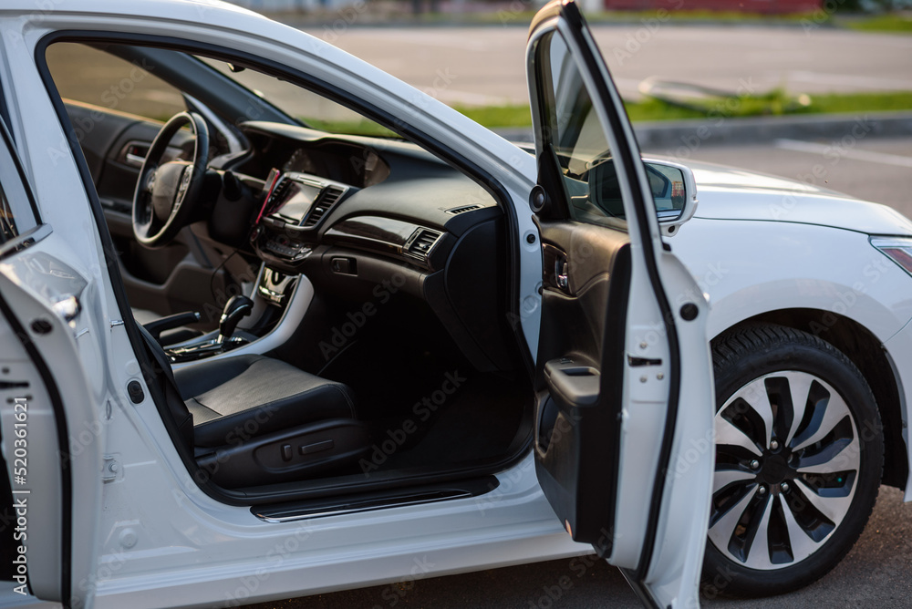 Side view of the open passenger door, mirror, dashboard of car. Right front door. A new modern shiny parked white car. Interior luxury car with tinted glass standing at parking. Modern car exterior. Side view of the open passenger door, mirror, dashboard of car. Right front door. A new modern shiny parked white car. Interior luxury car with tinted glass standing at parking. Modern car exterior.