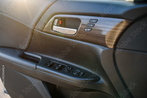 Car door control left panel. Leather new car interior. Car inside door chrome handle. Buttons to adjust driver's seat memory. Lifters control. Blocking the opening and closing of windows and doors. © Serhii