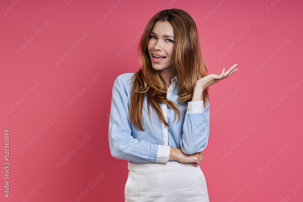 Beautiful young woman in smart casual clothing gesturing while standing against colored background Beautiful young woman in smart casual clothing gesturing while standing against colored background