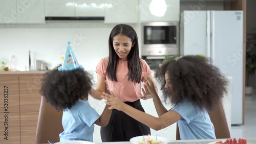 Happy family celebrating a birthday together, mother and daughter surprising her daughter with a mini birthday cake.