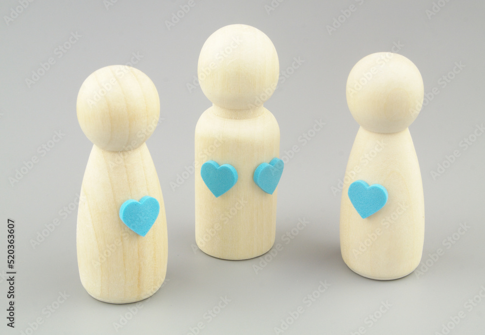 Man loving two women concept. Male figure with two heart stickers and female figures with one hearts on gray background. Man loving two women concept. Male figure with two heart stickers and female figures with one hearts on gray background.