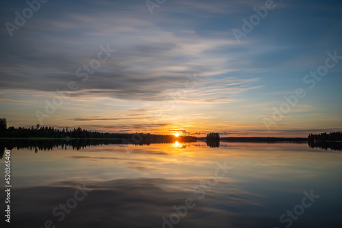 Tranquil golden hour cloud above the forest lake at sunset. Dramatic cloudscape. Symmetry reflections on the water  natural mirror.