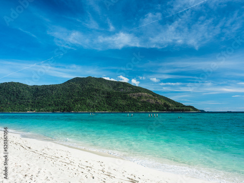 Scenic view of Sunrise Beach, Koh Lipe Island. White sand beach tropical island with crystal clear turquoise sea water against summer blue sky and Koh Adang Island background. Satun, Thailand.