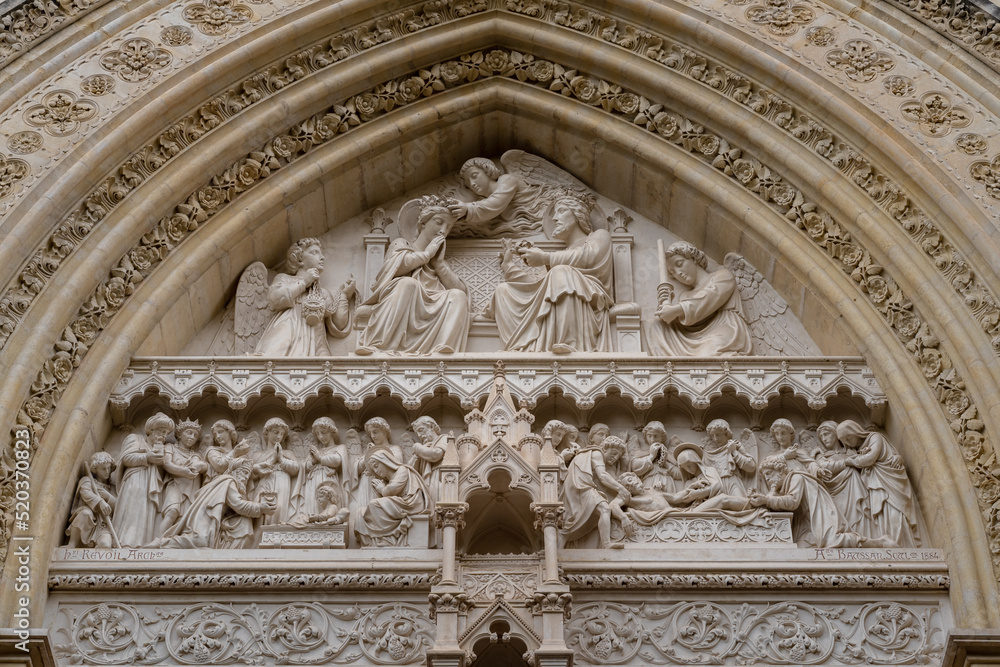 Closeup view of the tympanum showing the coronation of the Virgin Mary above the east entrance to ancient St Pierre or St Peter cathedral, tourism landmark of Montpellier, France