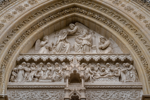 Closeup view of the tympanum showing the coronation of the Virgin Mary above the east entrance to ancient St Pierre or St Peter cathedral, tourism landmark of Montpellier, France