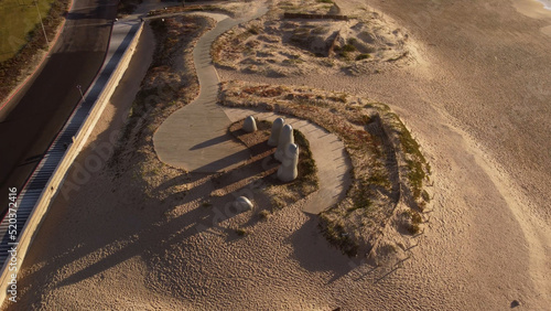 The Hand or La Mano sculpture on beach at sunrise and cityscape in background, Punta del Este in Uruguay. Top down view