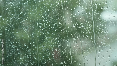 Close-up of Water Drops on Glass of Window. Drops Roll Down During Heavy Summer Rain. Thunderstorm with Strong Gusts of Wind. 4K.
