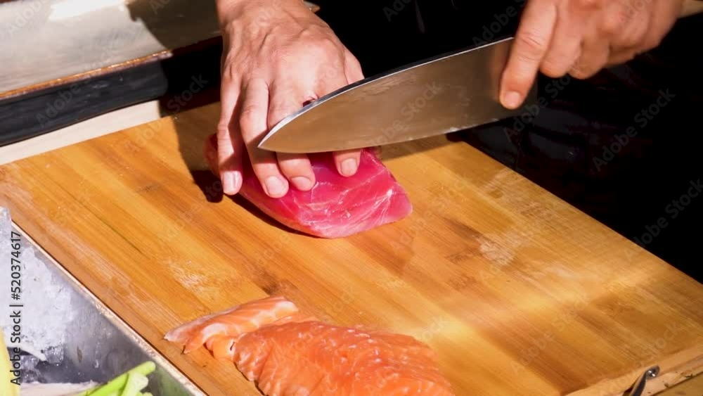 Professional male chef using a salmon butcher knife cuts a fresh orange