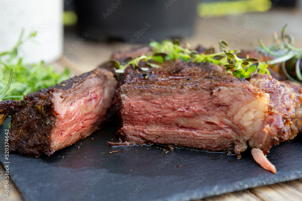 Grilled beef steak on wooden table top. Healthy food concept. Beef cut outdoors, garden kitchen, bbq grill patio Grilled beef steak on wooden table top. Healthy food concept. Beef cut outdoors, garden kitchen, bbq grill patio