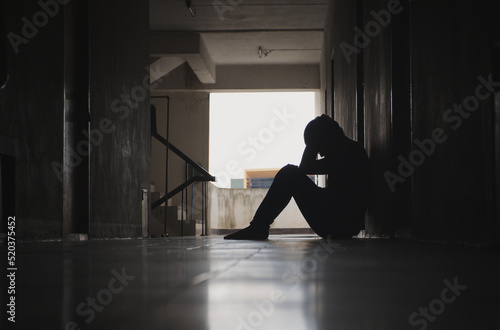 Silhouette of a depressed man sitting sadly in front of a room or corridor Concept Sad man Economic poison Plague Cry Drama Lonely and unhappy concept.