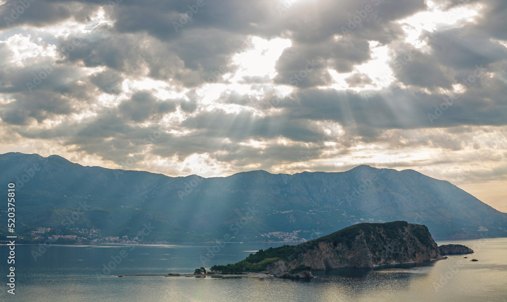 Landscape aerial view of the bay of old historical city Budva, mountains and forests of Montenegro, on dramatic sky and Sveti Nikola island