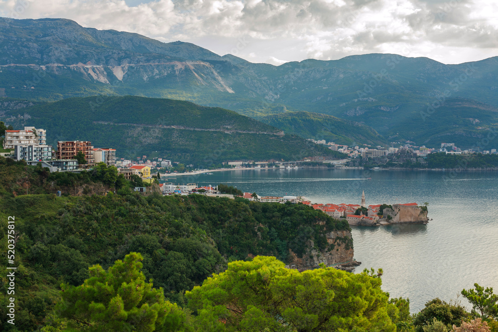Landscape aerial view of bay of the old historical city Budva, mountains and forests of Montenegro, on background of dramatic sky