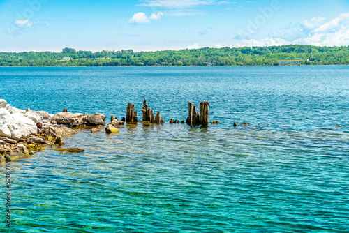 Landscape of the Huron Lake water and old withered wooden dock posts or marina wreck at sunny day in Georgian Bay near Spirit Rock Conservation Area at Wiarton, Ontario, Canada. © desertsands